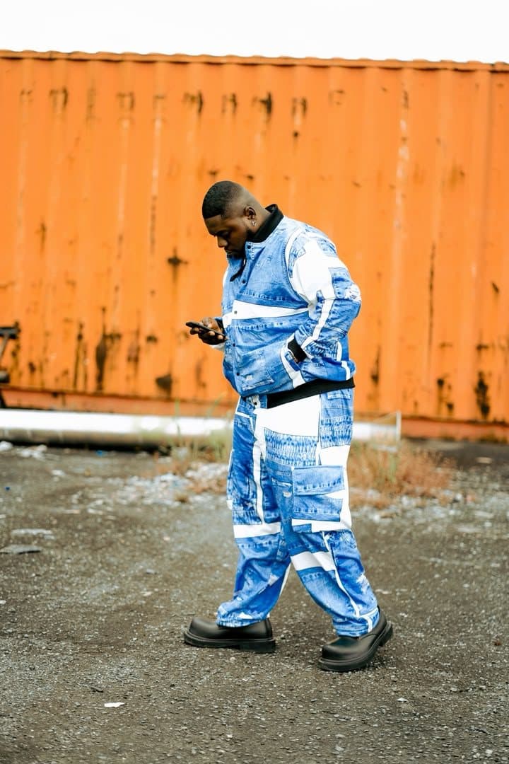 Woriidem in a denim-print two-piece walking past an orange shipping container