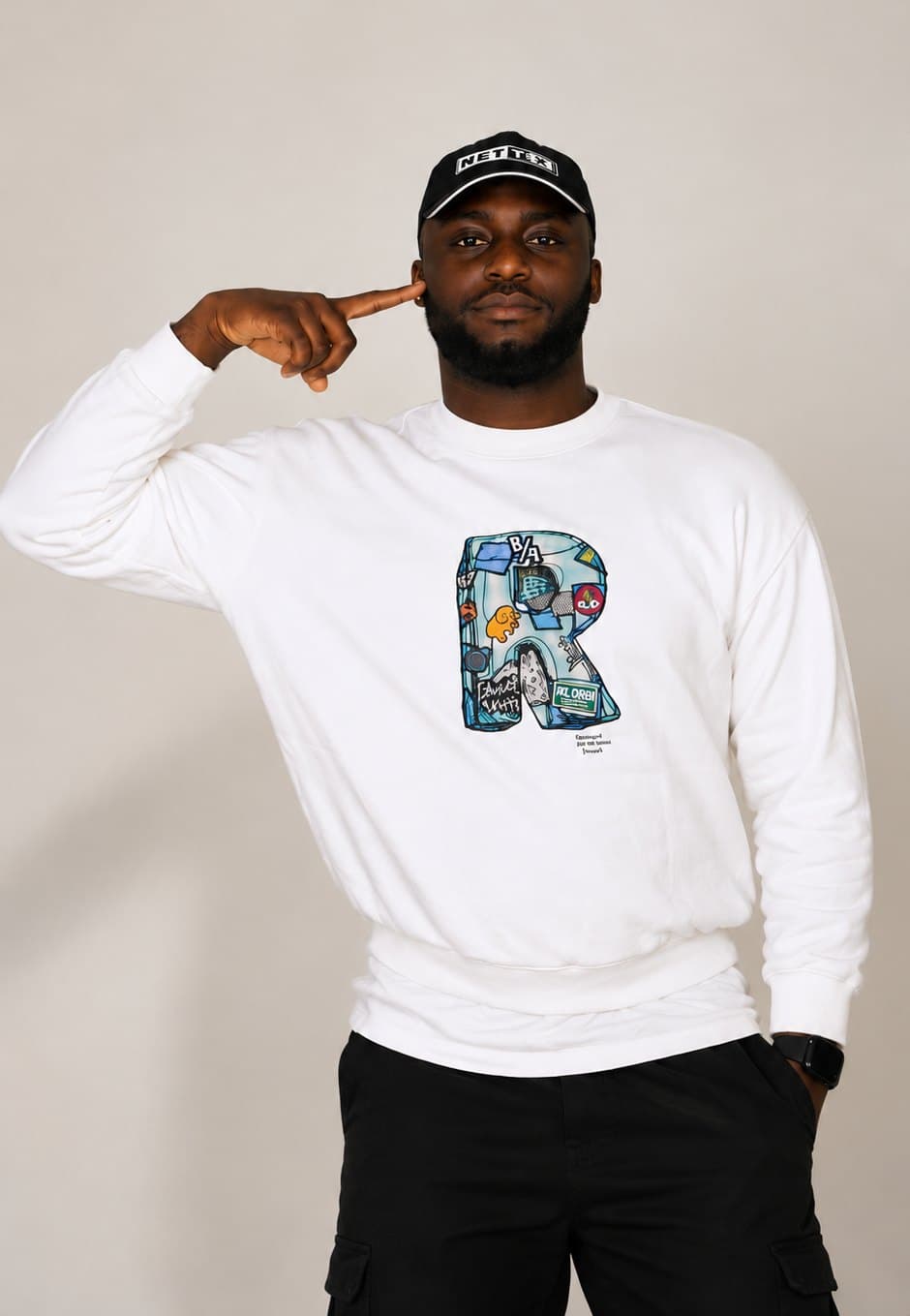 Woriidem in a white sweatshirt and black cap, finger to his temple