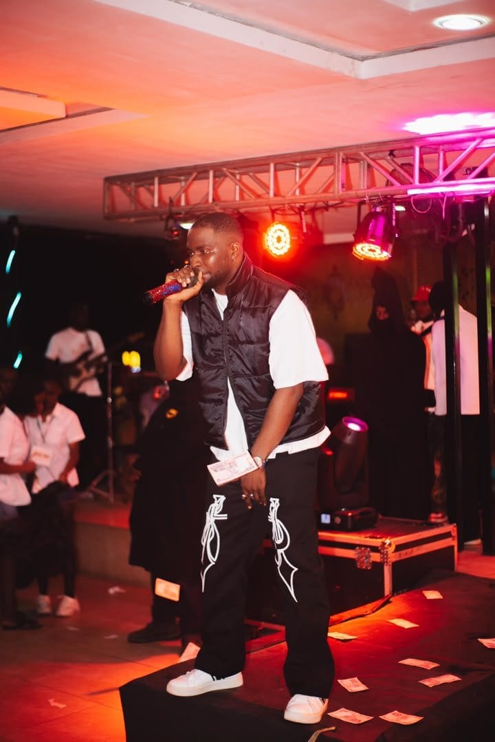 Woriidem on stage in a purple floral shirt, microphone raised to the crowd